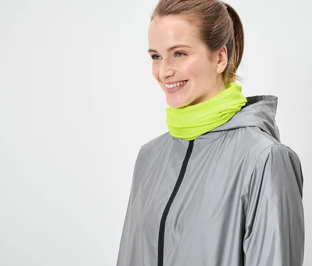 Une femme portant une veste grise et un cache-cou vert néon.