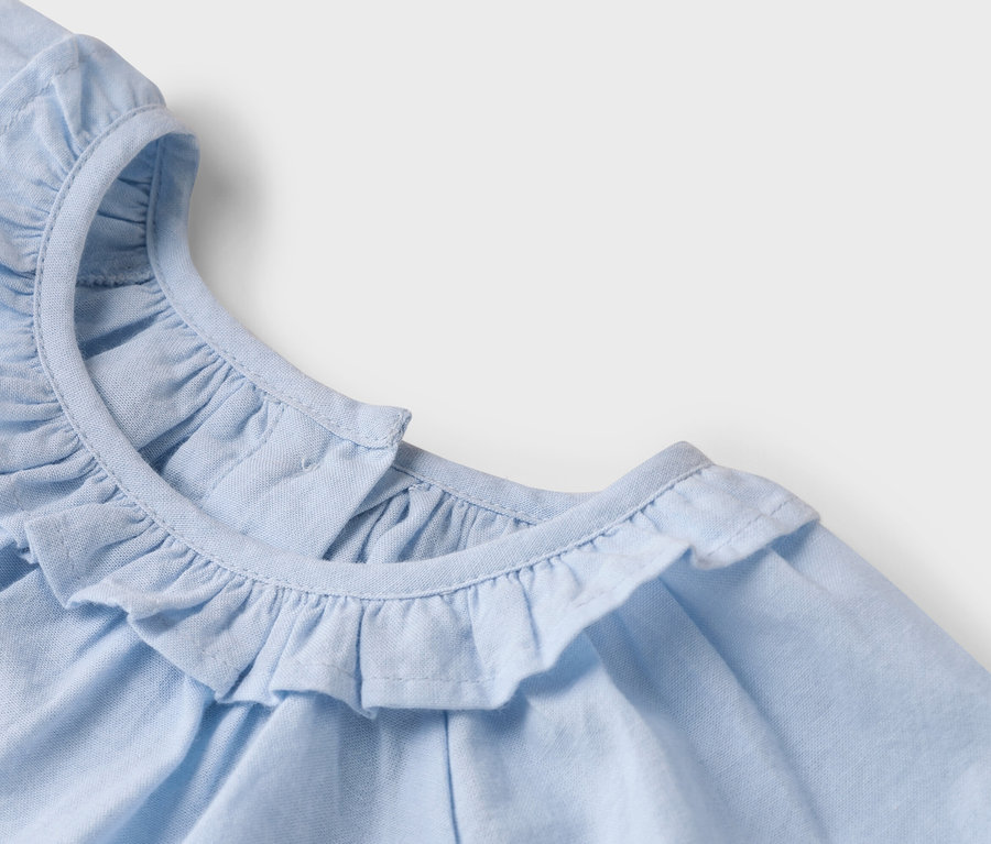 Vue détaillée d'un haut en tissu bleu clair avec un col à volants.