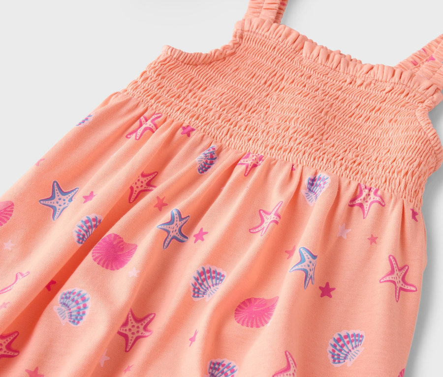 Gros plan sur une robe orange à motifs d'étoiles de mer et de coquillages.