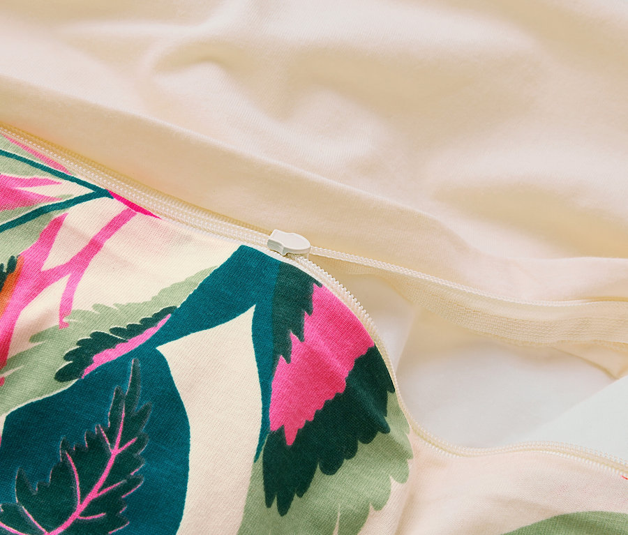 Gros plan sur une housse de couette partiellement ouverte avec une fermeture éclair et un motif de feuilles tropicales.