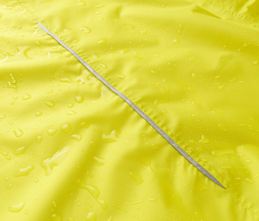 Gros plan d'un imperméable jaune avec fermeture éclair argentée et gouttes d'eau.