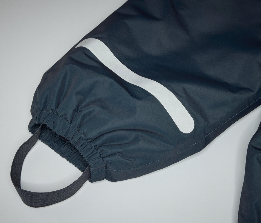 Gros plan sur le bas d'un pantalon bleu marine avec ourlet élastique, passant de pied et bande réfléchissante.