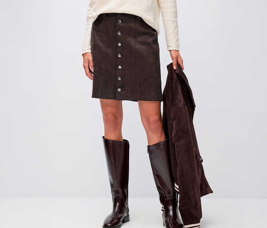 Femme portant une jupe de velours Street One, un haut couleur crème et des bottes marron.