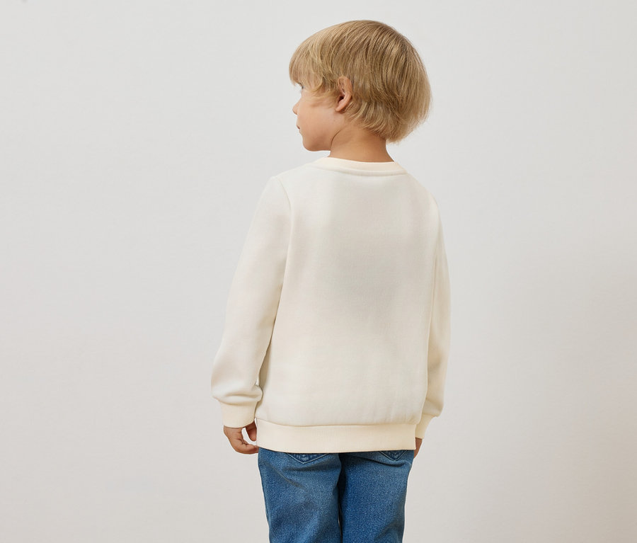 Vue arrière d'un enfant blond portant un sweat-shirt d'enfant avec intérieur gratté, soleil et un jean bleu.