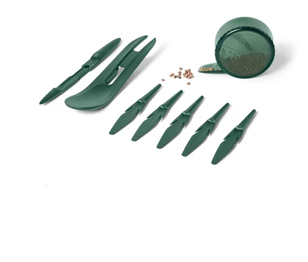 Ensemble d'outils de jardinage verts comprenant des outils de plantation et un récipient avec des graines sur fond blanc.