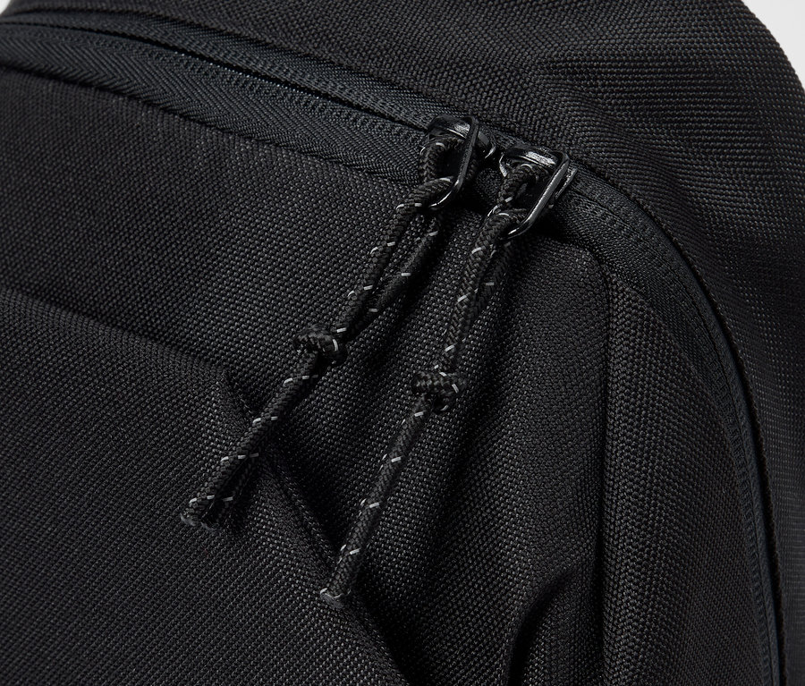 Gros plan d'un sac à dos noir avec fermeture éclair et cordon de serrage.