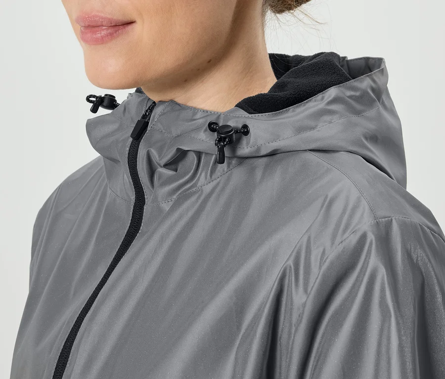 Gros plan d'une femme portant un imperméable gris à capuche avec une fermeture éclair noire.