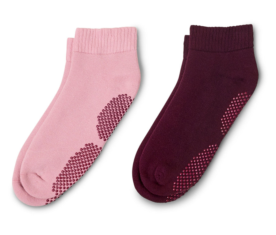 Deux paires de chaussettes courtes, une rose et une bordeaux, toutes deux avec des picots antidérapants sur la semelle.