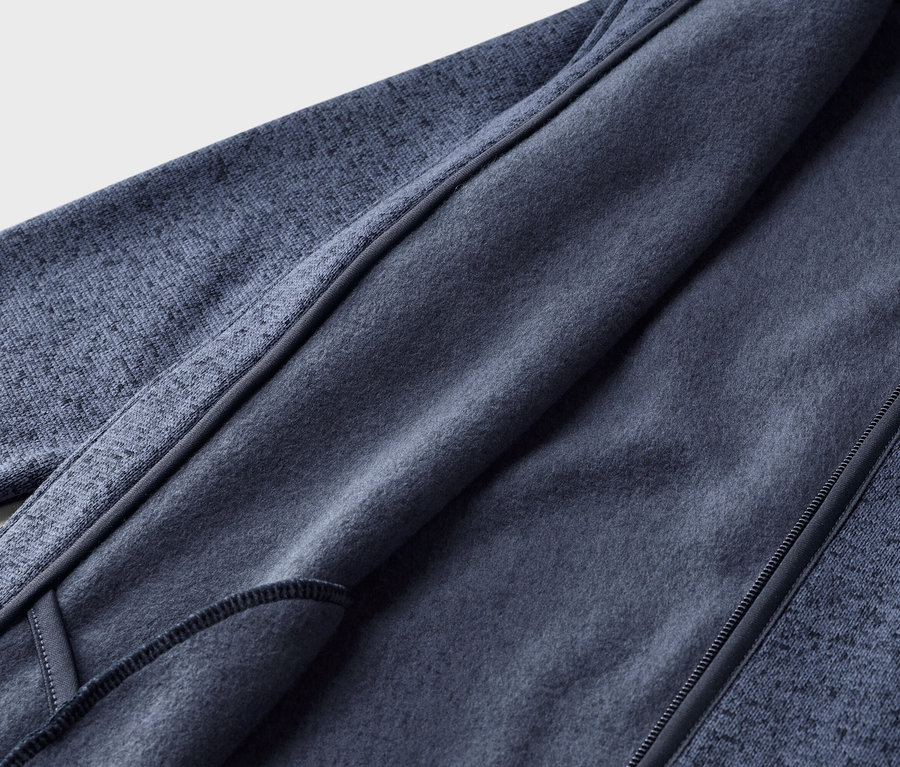 Gros plan d'une veste polaire bleu foncé, partiellement ouverte pour montrer la doublure intérieure douce et unie bleue et le tissu extérieur texturé.