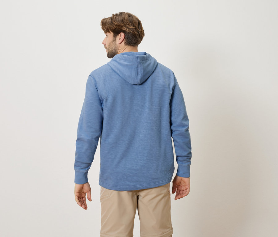 Un homme vu de dos portant un sweat à capuche bleu et un short beige.