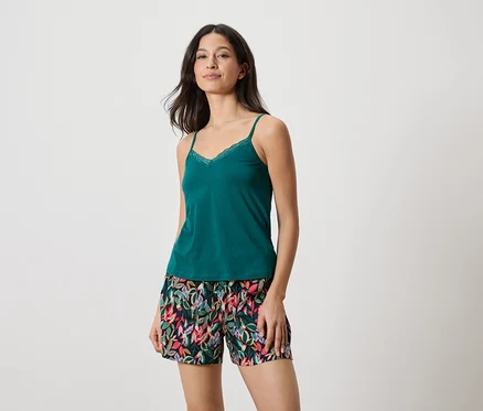 Femme portant un débardeur vert avec de la dentelle et un short à imprimé de feuilles.