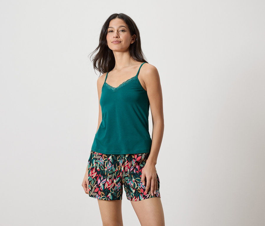 Femme portant un débardeur vert avec de la dentelle et un short à imprimé de feuilles.