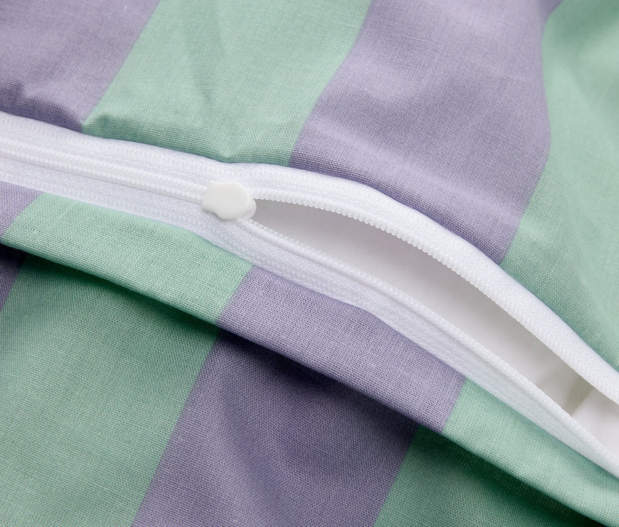 Gros plan d'une fermeture éclair partiellement ouverte sur une housse en tissu rayé violet et vert.