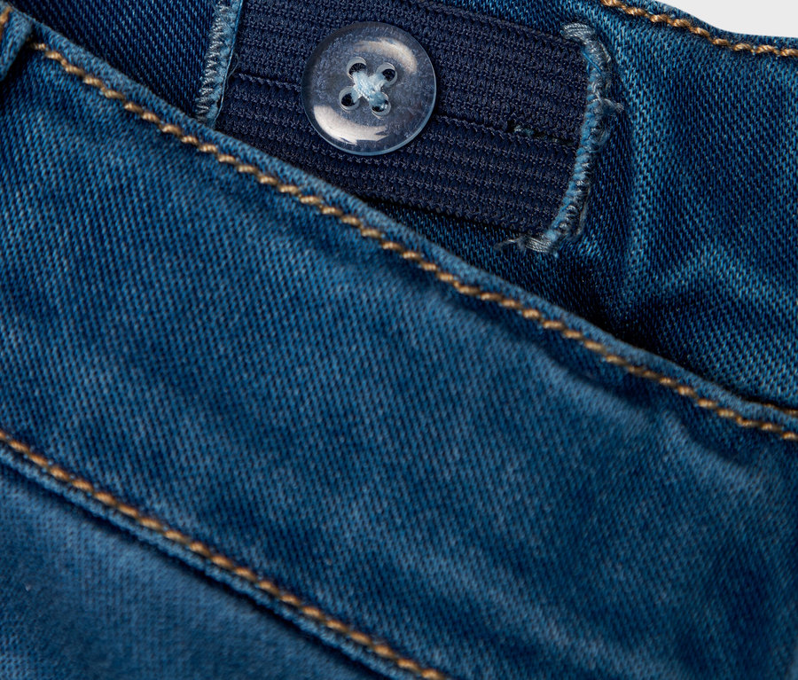 Gros plan d'un jean bleu avec un bouton de taille réglable.