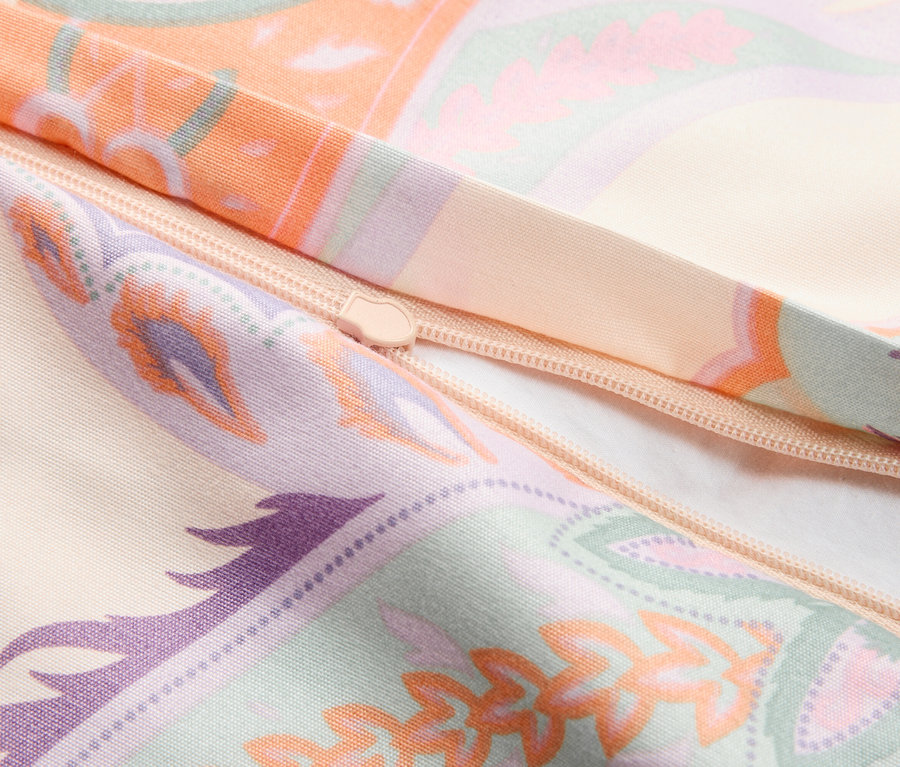 Gros plan sur une fermeture éclair sur un tissu beige avec des motifs orange et violet.