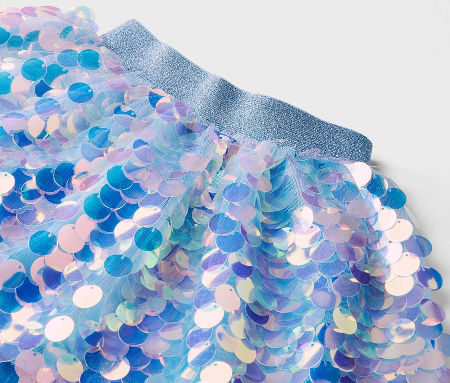 Gros plan d'une jupe en tulle avec des paillettes bleues et une ceinture élastique scintillante.