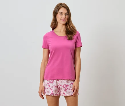 Femme portant un t-shirt rose et un short à fleurs.