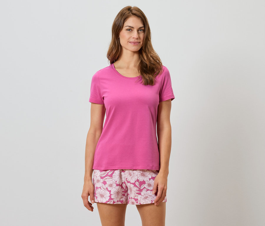 Femme portant un t-shirt rose et un short à fleurs.