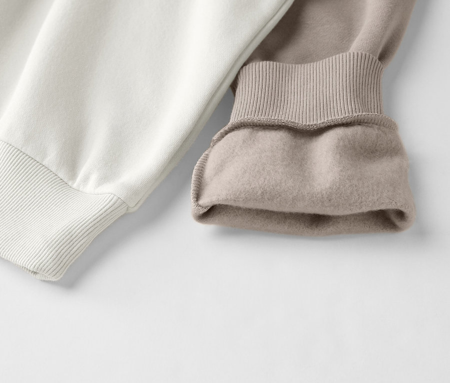 Gros plan sur un sweat-shirt bicolore blanc et beige avec des poignets côtelés.