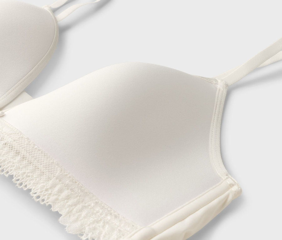 Vue détaillée d'un soutien-gorge blanc avec de la dentelle et de fines bretelles.