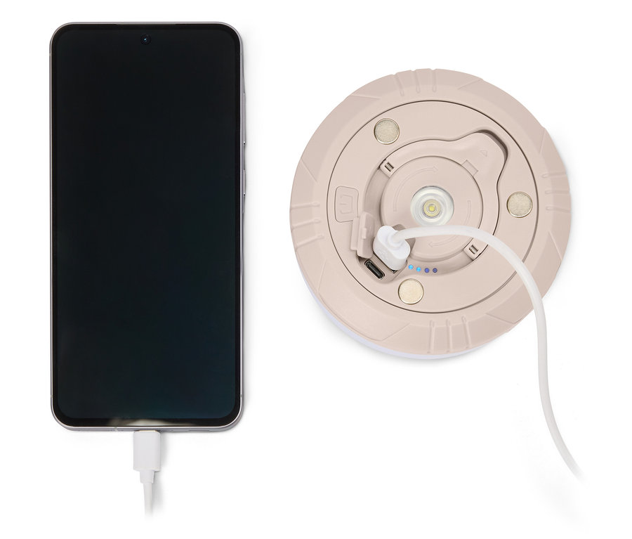 Téléphone en charge avec un chargeur beige rond avec un câble blanc.