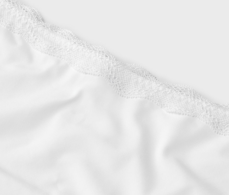 Vue détaillée d'un tissu blanc avec de la dentelle blanche sur le dessus.