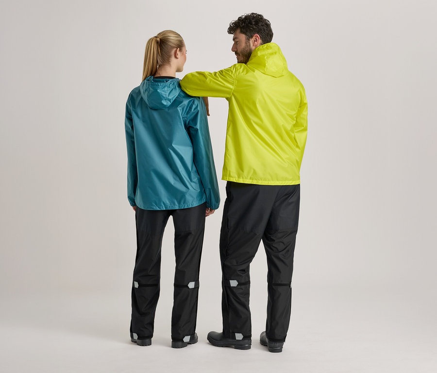 Vue arrière d'une femme en veste de pluie turquoise et d'un homme en veste de pluie jaune, tous deux portant un pantalon de pluie noir sur fond clair.