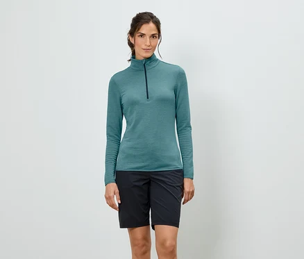 Femme portant un T-shirt turquoise à manches longues avec fermeture éclair et un short noir.