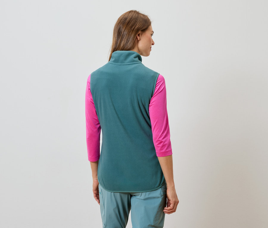 Vue arrière d'une femme aux longs cheveux bruns portant un gilet en polaire turquoise, un T-shirt rose à manches longues et un pantalon turquoise.