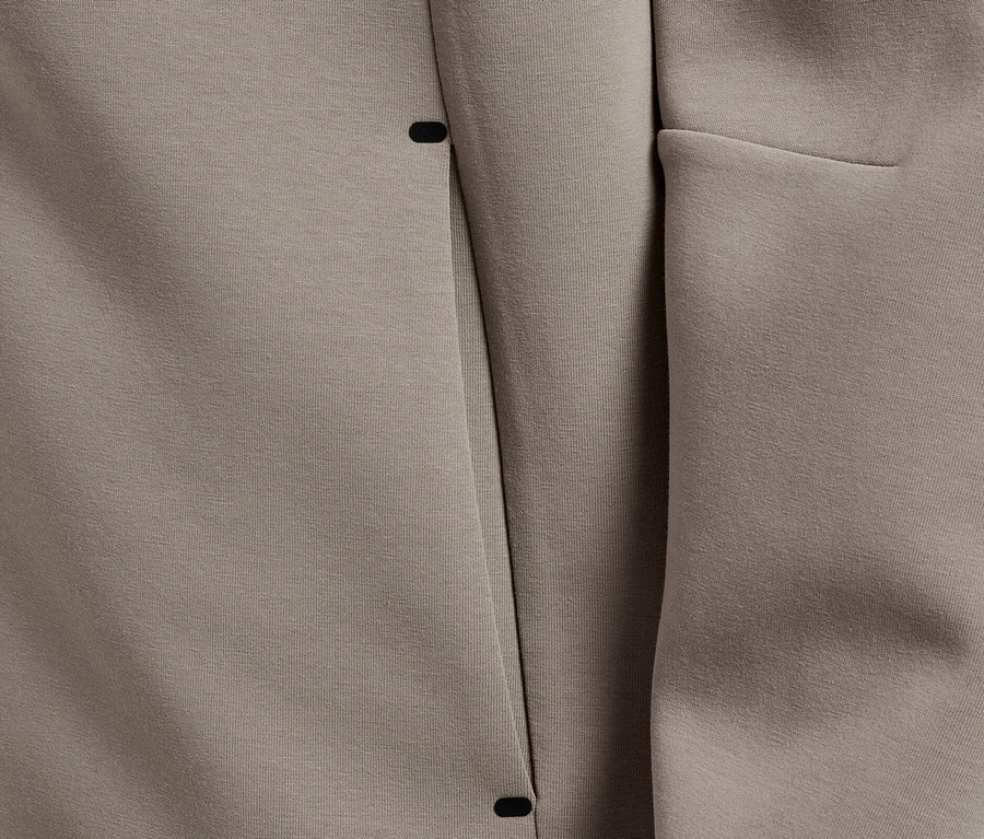 Gros plan sur un sweat à capuche taupe au design minimaliste avec une poche dissimulée.
