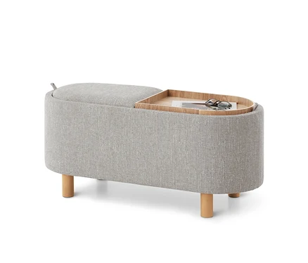 Banc rembourré gris avec pieds en bois, plateau en bois amovible avec magazine et lunettes de soleil, et compartiment de rangement relevable.