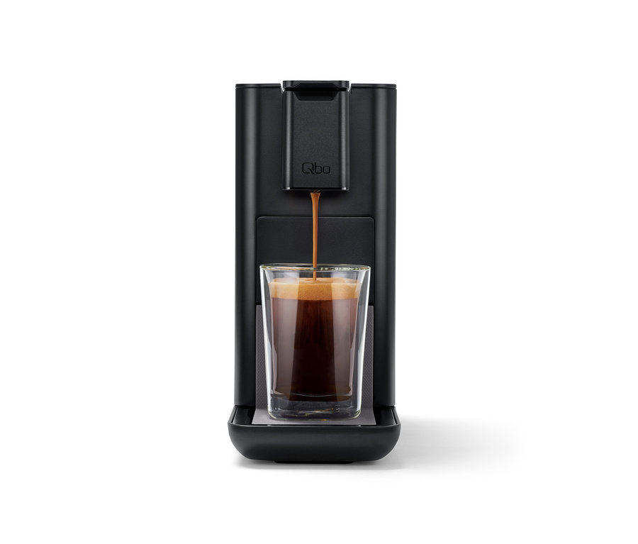 Le café coule d'une machine à café Qbo ICONIC Dark Chrome dans un verre.