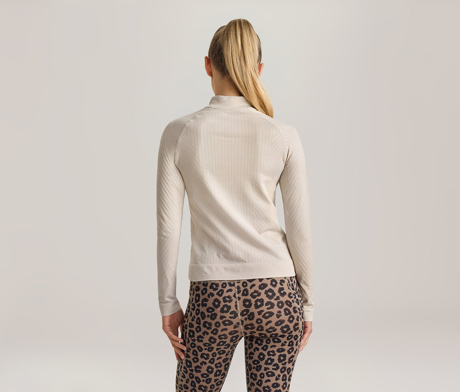 Femme vue de dos, portant un haut à manches longues côtelé beige clair avec un col montant et un legging imprimé léopard.