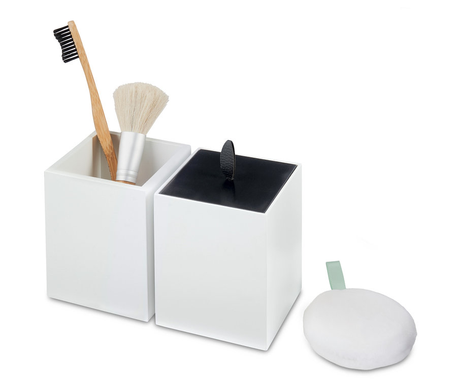 Deux organisateurs blancs, un avec une brosse à dents et un pinceau de maquillage, à côté une éponge blanche.