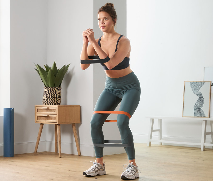 Femme faisant des squats avec 3 bandes d'entraînement.