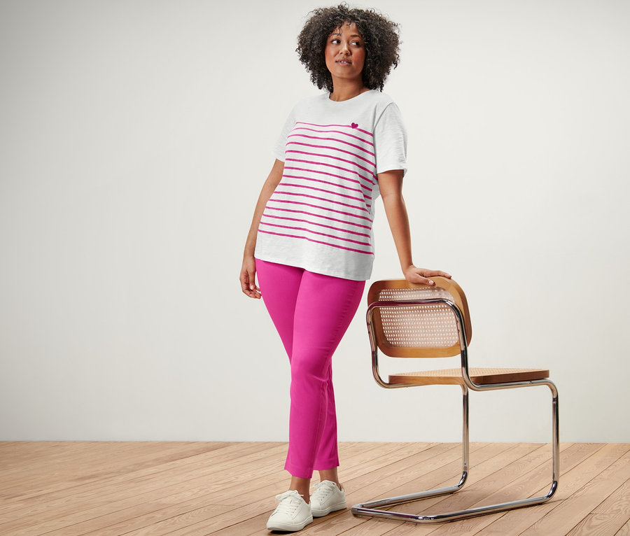 Femme posant dans un t-shirt rayé et un pantalon stretch rose.