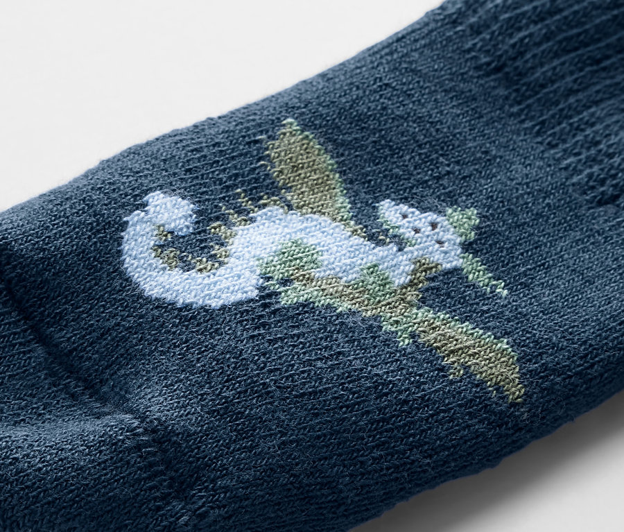 Gros plan d'une chaussette bleue pour bébé avec une broderie de dragon.