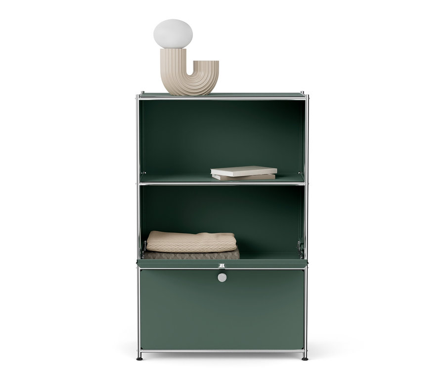 Commode métallique « CN3 » à deux abattants. Un livre blanc repose sur l'étagère supérieure, une couverture beige pliée repose sur l'étagère du milieu.