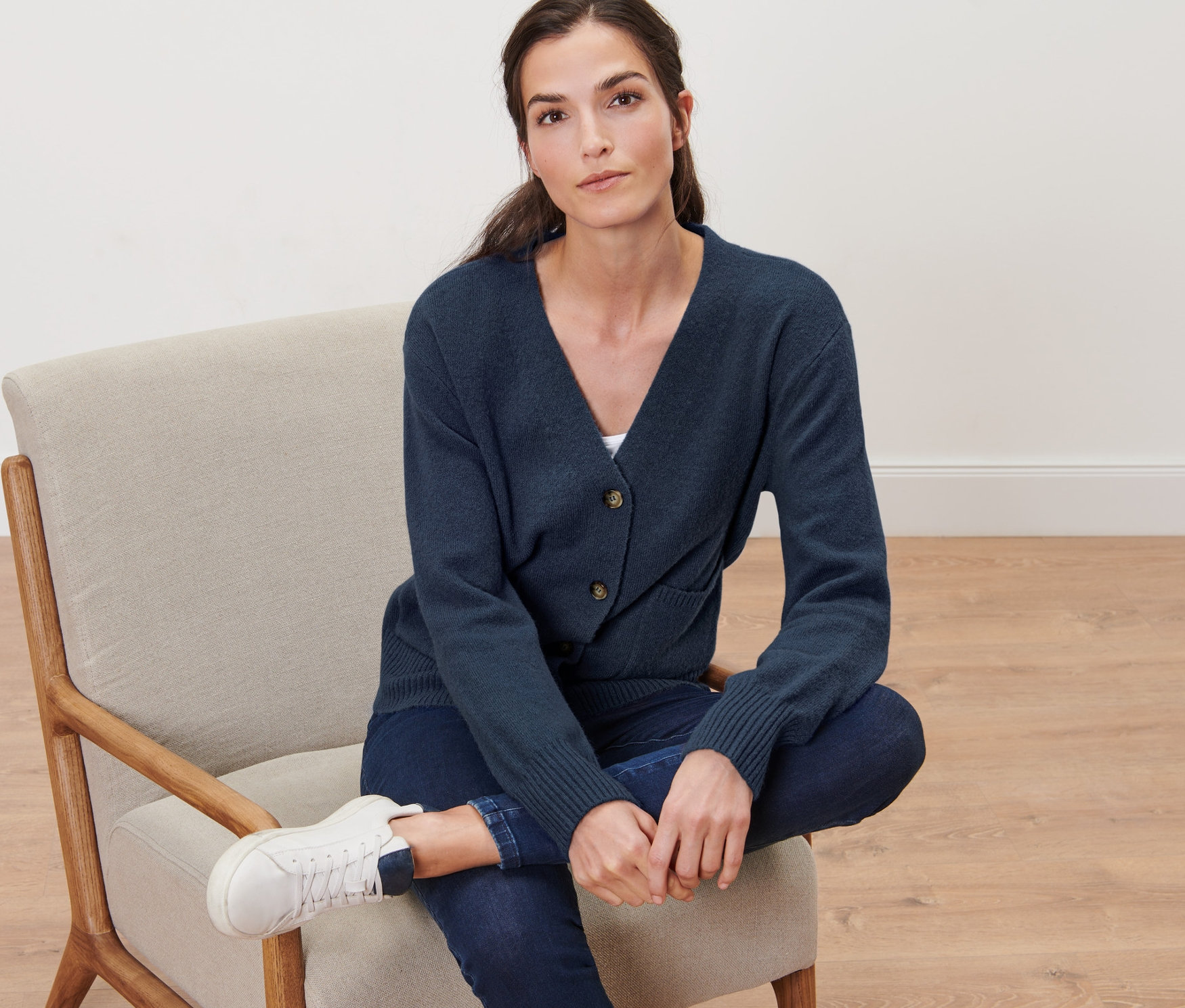 Femme assise sur une chaise, portant une veste en tricot avec laine bleu foncé.