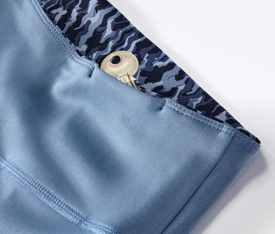 Détail d'un legging de sport réversible bleu/bleu clair avec une clé dans la poche.