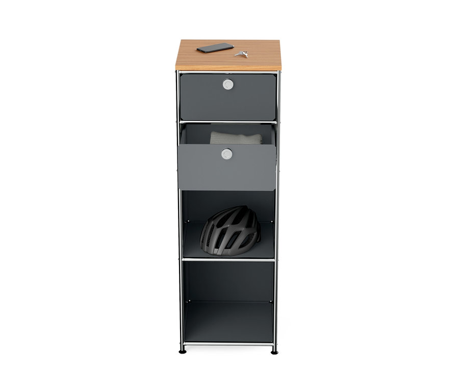 Commode étroite en métal gris « CN3 » avec plateau en bois, sur lequel reposent un téléphone et des clés. Un vêtement blanc est visible dans le tiroir ouvert et un casque sur l'étagère du dessous.