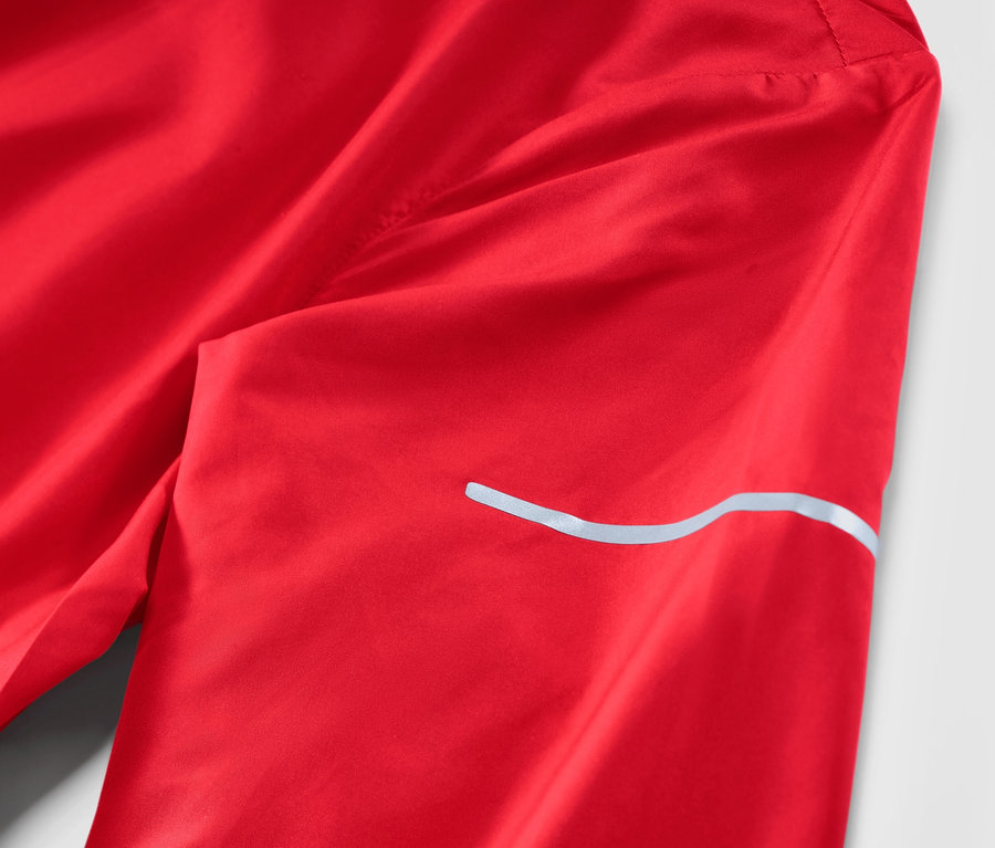 Détail d'une veste de course légère rouge.