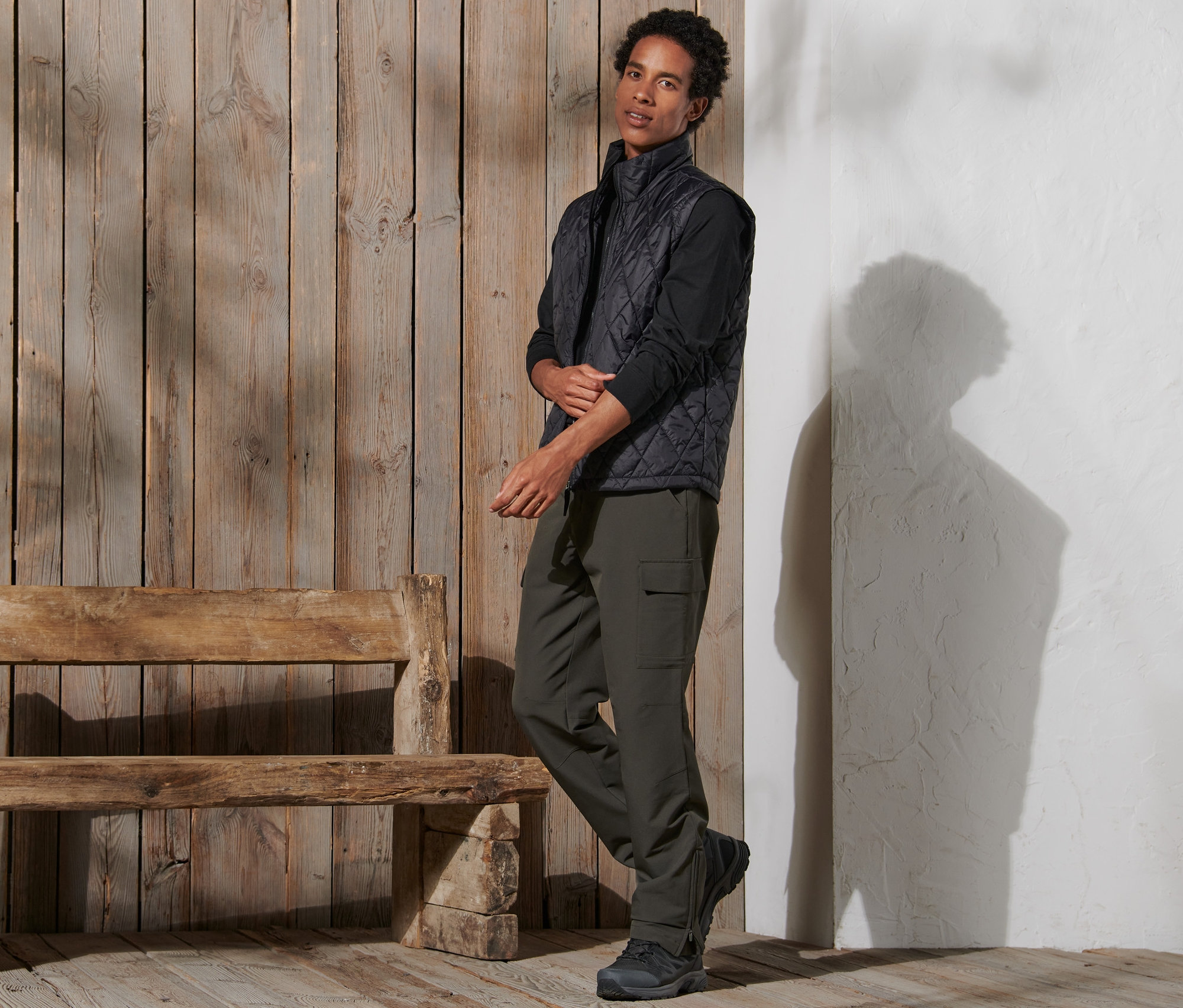 Un homme debout portant un pantalon thermique, un gilet et des chaussures.
