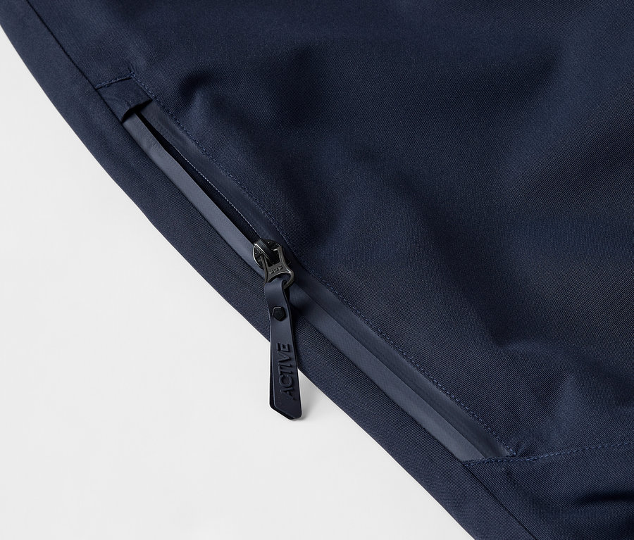 Gros plan sur une veste bleu foncé avec fermeture éclair et logo.