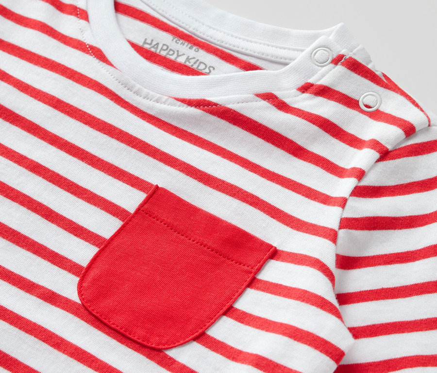 Gros plan sur un t-shirt à manches longues pour enfant avec des rayures rouges et blanches et une poche rouge.