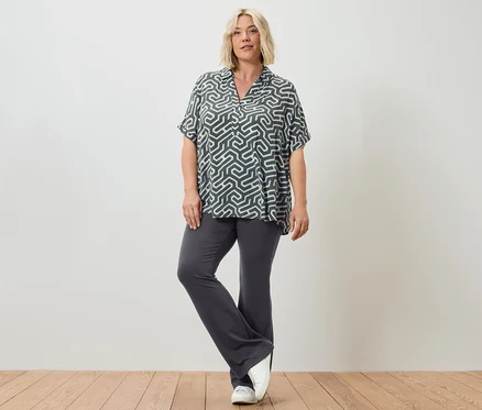 Une femme pose en legging évasé et une blouse imprimée.