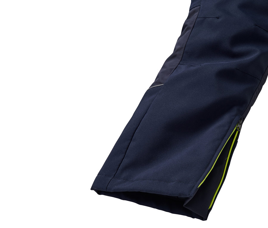Détail d'un pantalon avec une fermeture éclair ouverte et une bordure vert citron.