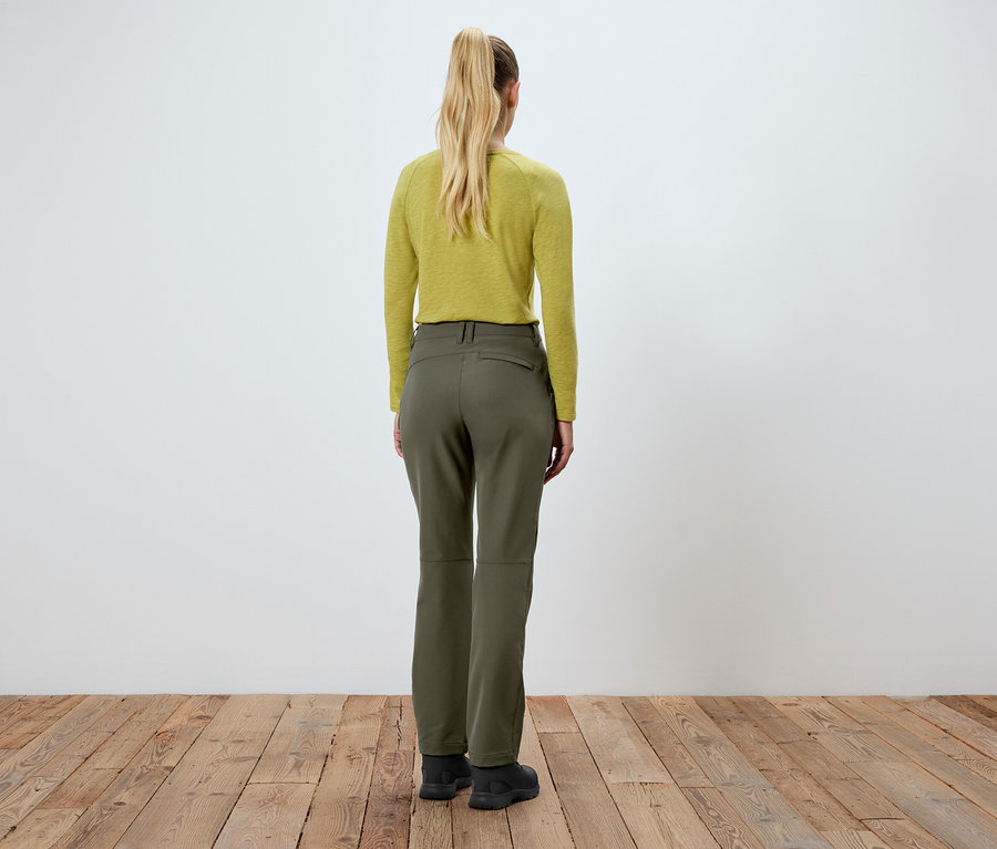 Une femme, vue de dos, porte un pantalon vert et un haut jaune.