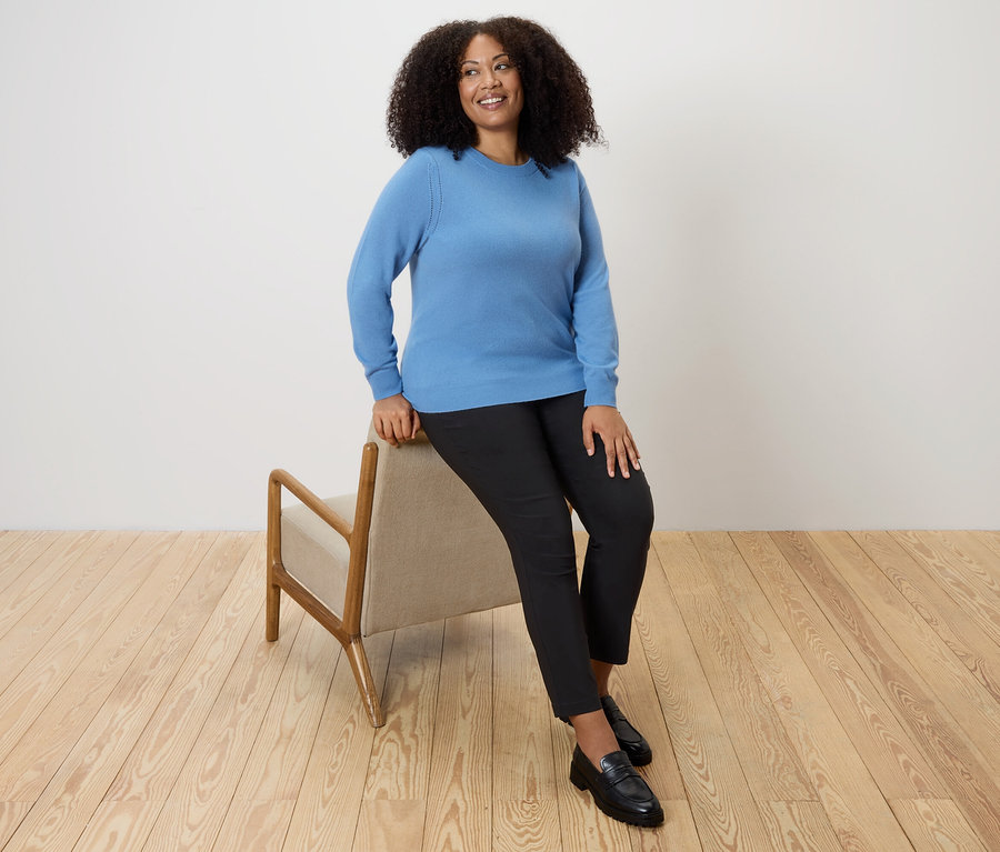 Femme assise sur une chaise portant un pull bleu en maille fine avec du cachemire.