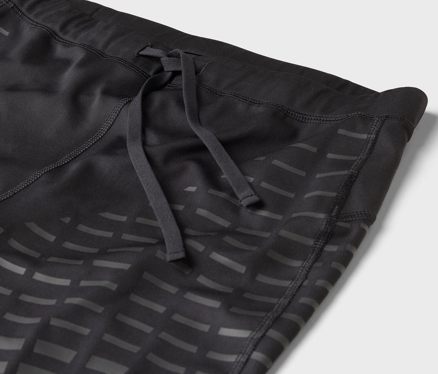 Gros plan sur un legging de sport noir avec cordon de serrage et motif géométrique.
